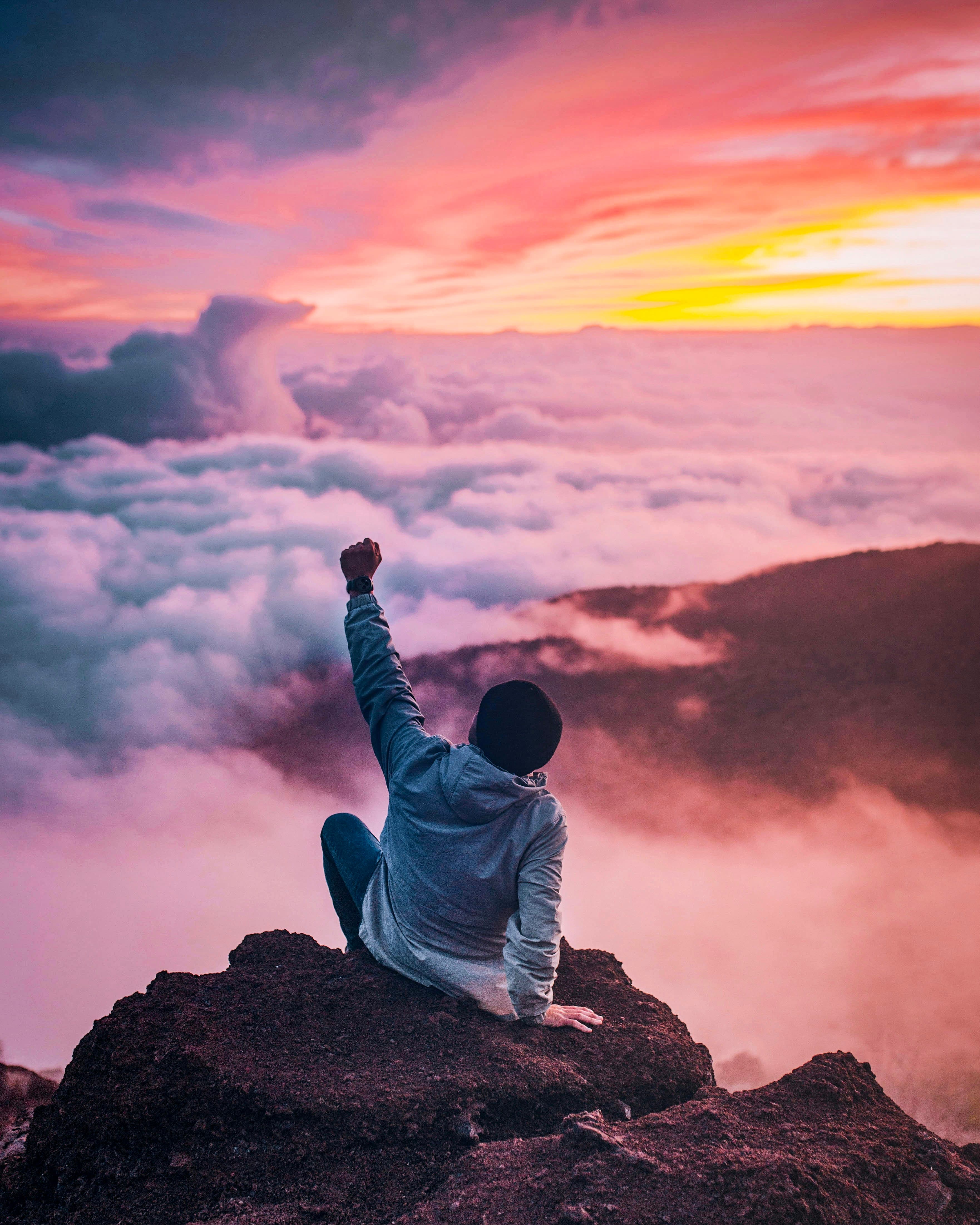 Confident man standing on mountain peak at sunrise